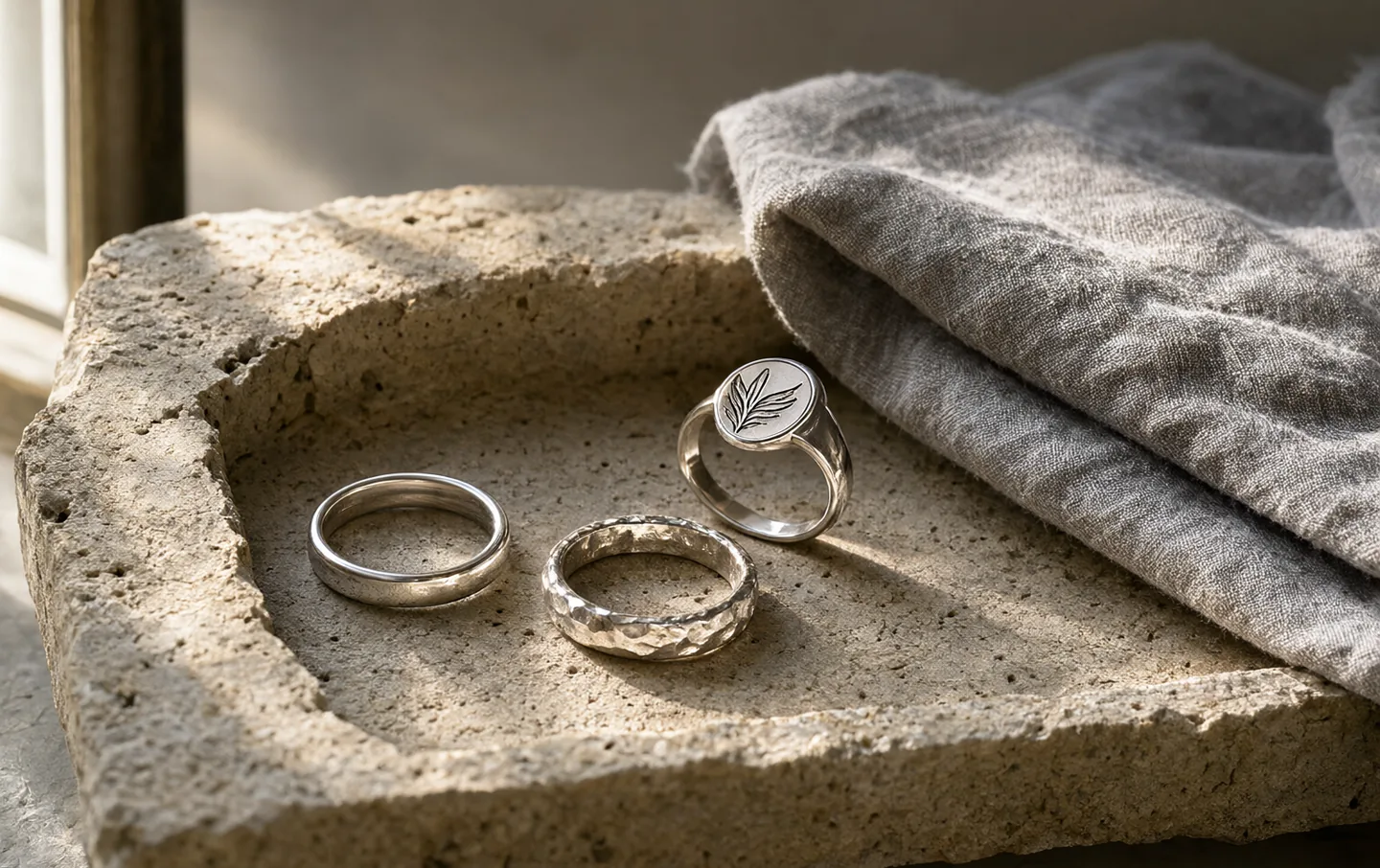 Three simple sterling silver rings on a rough travertine tray